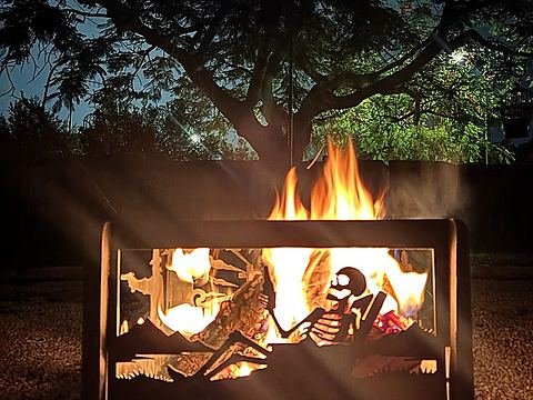Fire glowing through a steel panel of a skeleton kicked back with a bottle in the mountains