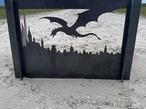 Steel panel cut with a dragon flying over a castle skyline