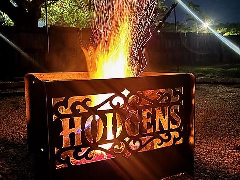 Custom steel fire pit panel with a family name in western lettering framed by scrollwork