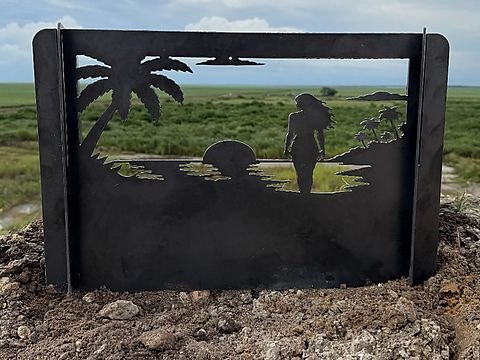 Steel fire pit panel with a palm tree, setting sun and a woman on the shoreline cut through the plate