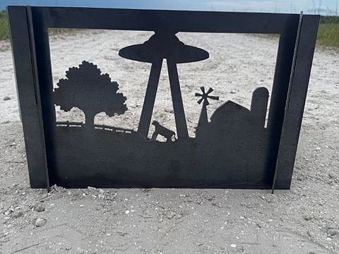 Steel panel cut with a flying saucer lifting a cow from a farmyard